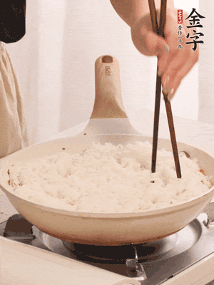 把瀝干水分的米飯均勻鋪在上面，筷子戳幾個(gè)洞，以便透氣，轉(zhuǎn)小火蓋上蓋子燜至水分收干，大概10分鐘。